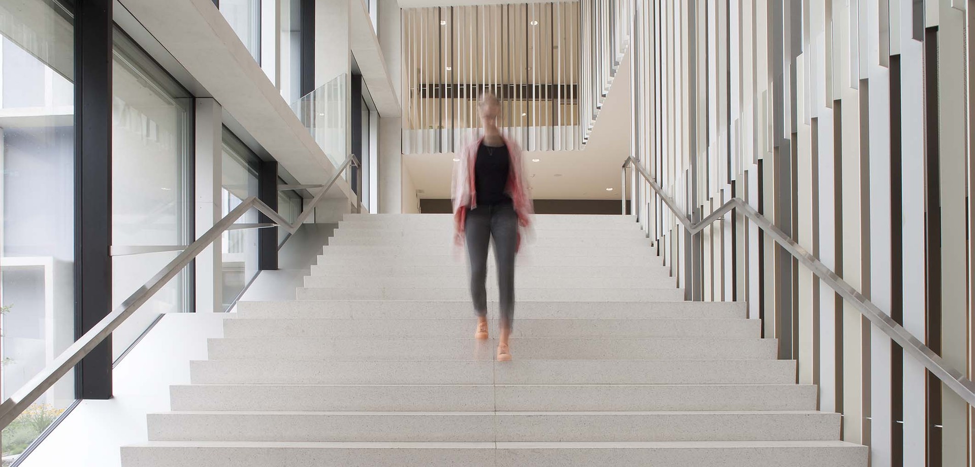 Ein Frau geht die breite Treppe des Phönix-Hauses hinunter